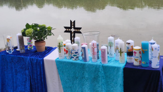 Bunte Taufkerzen, persönlich und farbenfroh von den Famlien gestaltet, schmücken den Altar zum Tauffest am Augsburger Kuhsee.