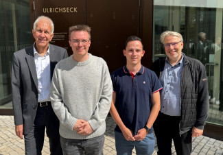 Zwei neue Auszubildende und die Geschäftsleitung vor dem Eingang am Ulrichseck